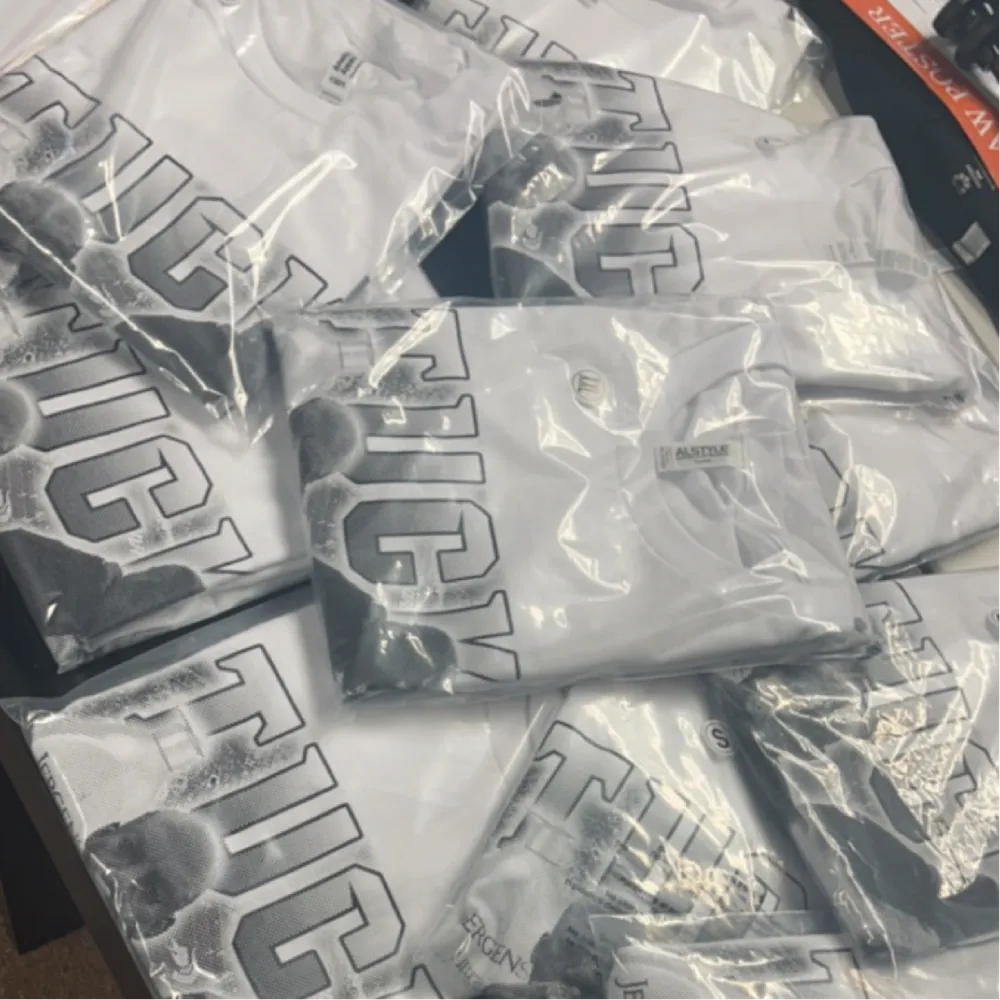 Stack of white screen-printed t-shirts bagged and ready to ship